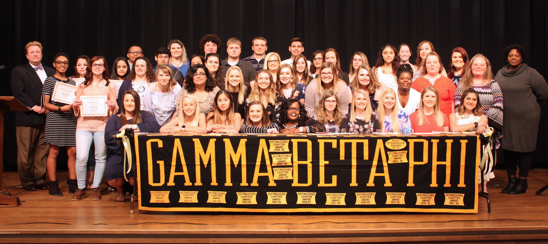 group of students behind a large sign that reads gamma beta phi.