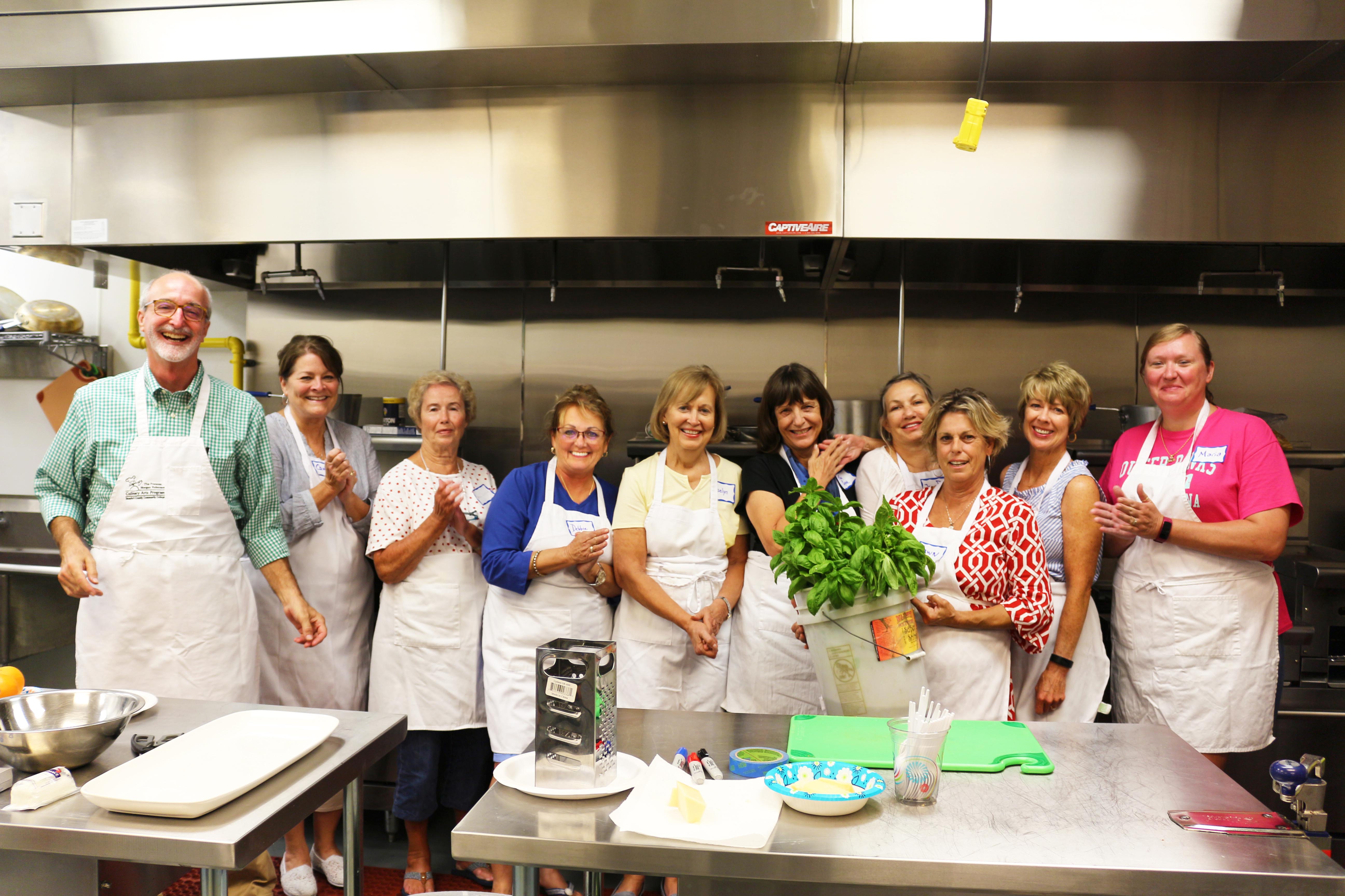 A cooking class lined up holding a bucket of basil.