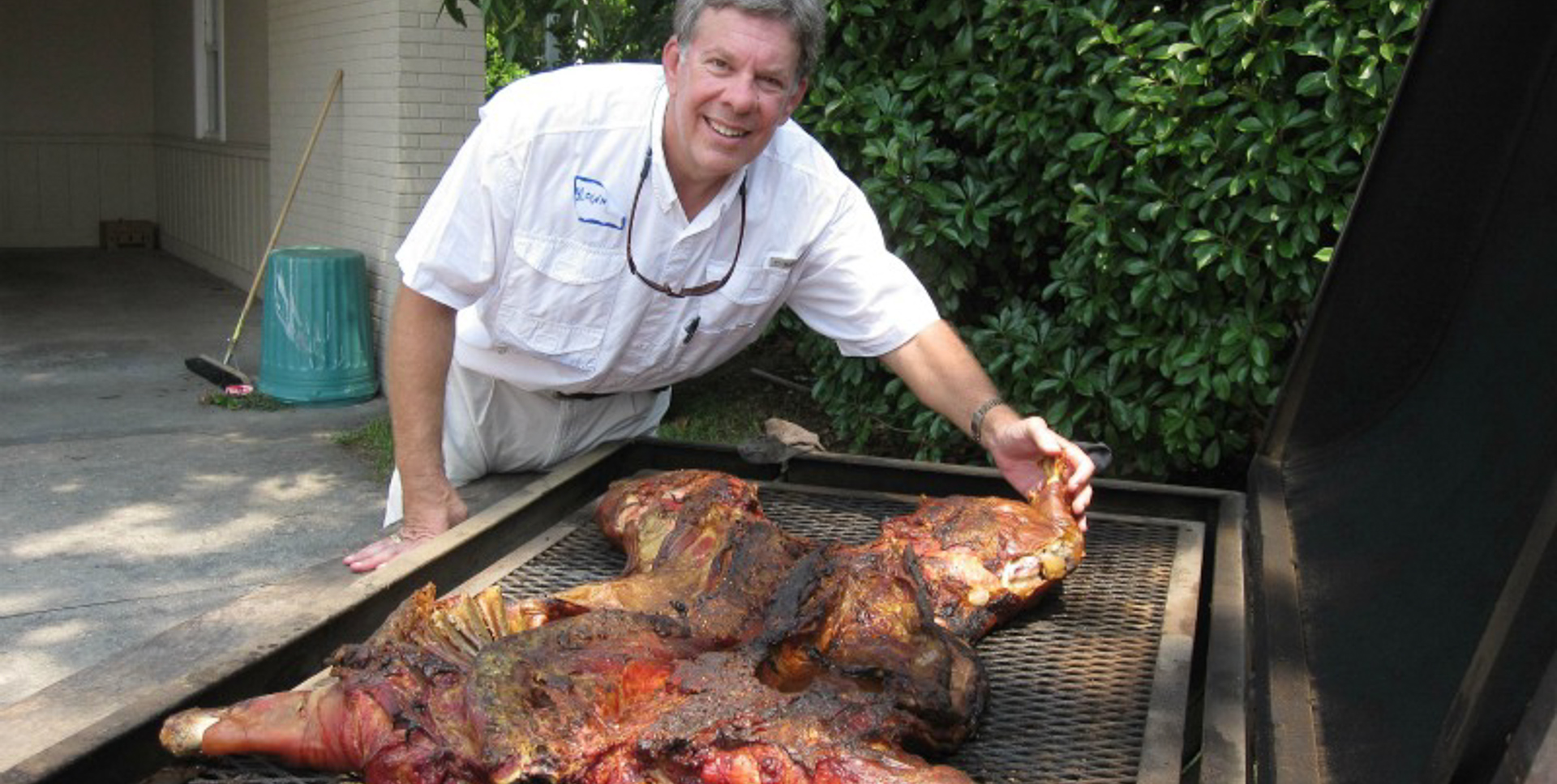 A roasted pig carcass with a person touching it.
