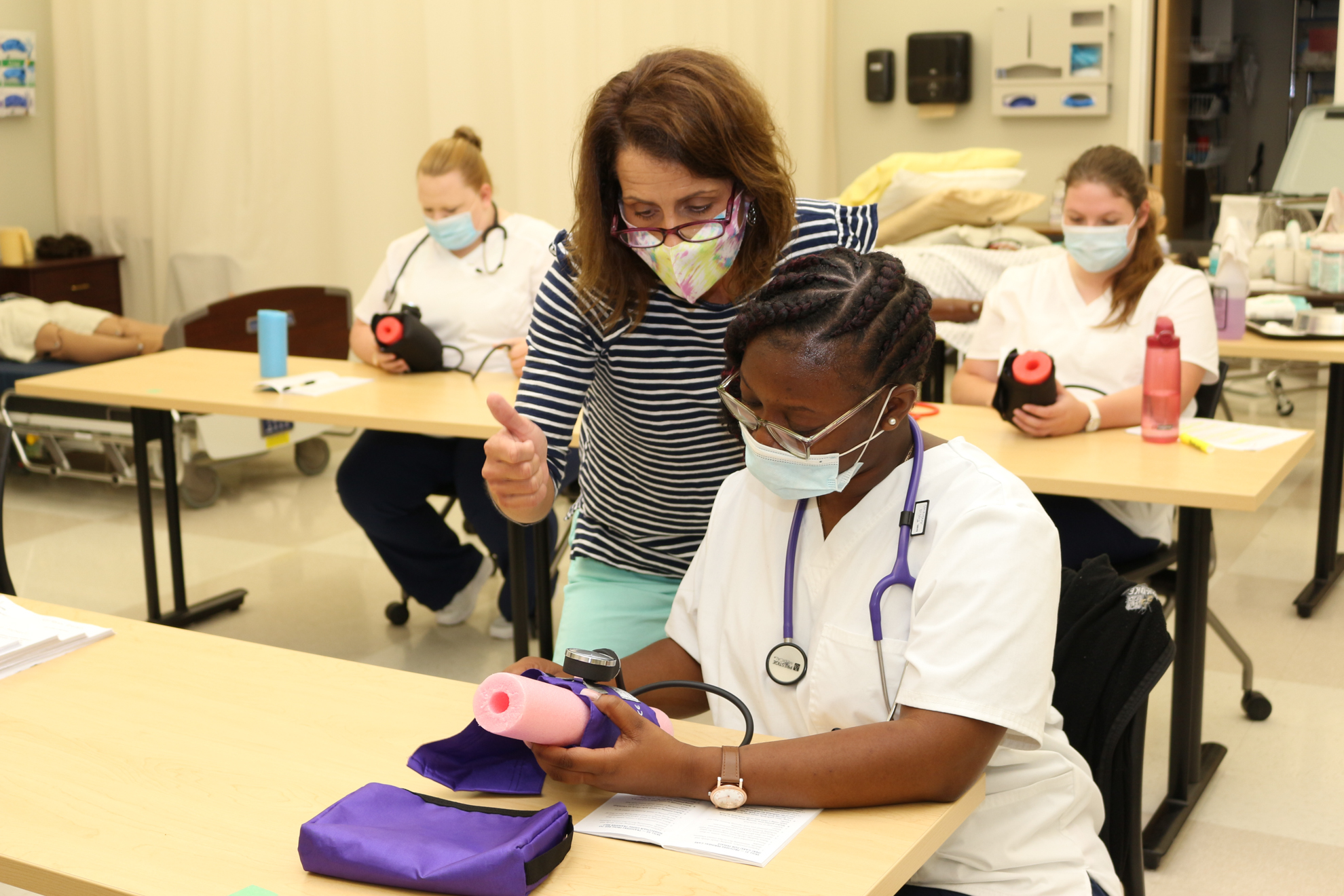 a teacher helping a student check blood pressure