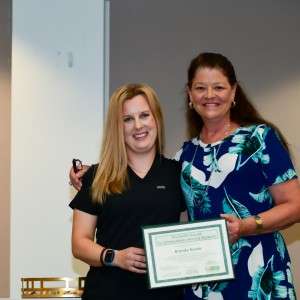 2 women on stage with certificate