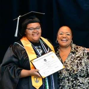 2 people smiling holding a diploma