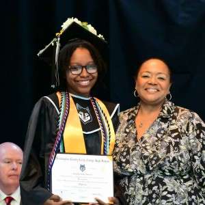 3 people on stage with diploma