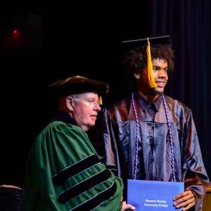2 men on stage wit certificate
