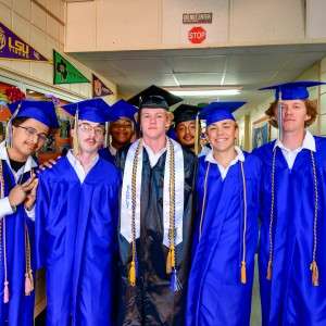 Men in cap & gown with academic ribbons.