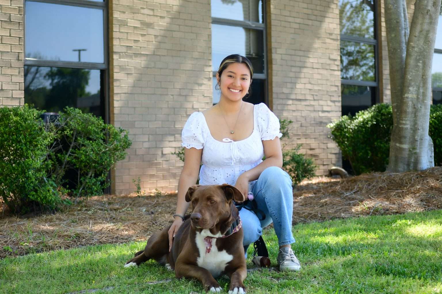 Female student petting dog in front of building