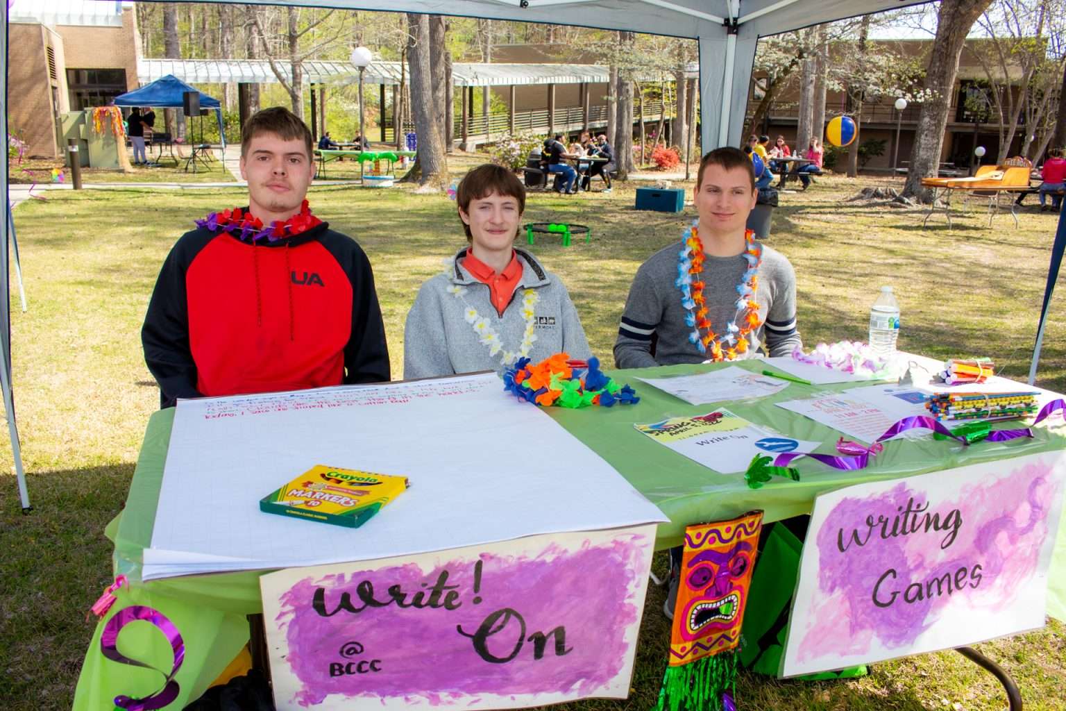 3 students sitting at a table at an outdoor event.