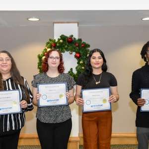 4 people on a stage holding certificates