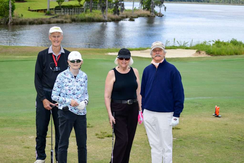 4 golfers in front of pond