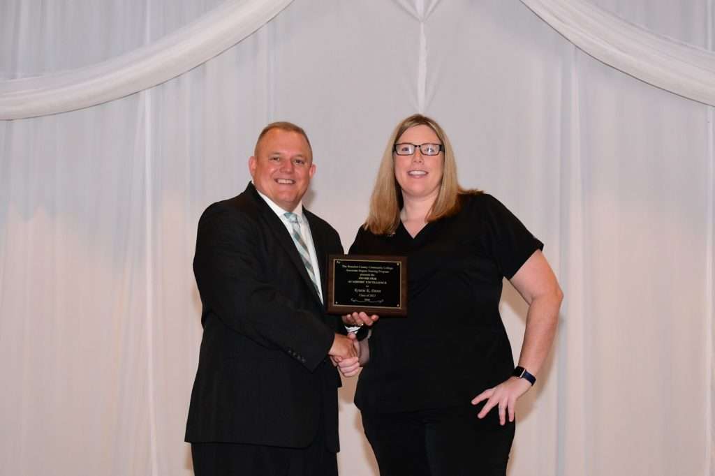 2 people shaking hands with an award