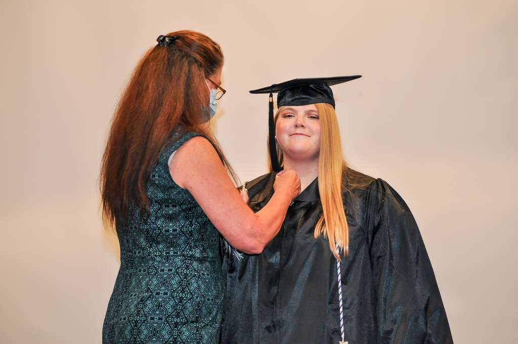 one person pinning another one in cap and gown