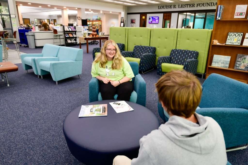 2 people sitting in a library