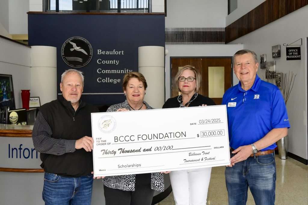 four people holding a big check