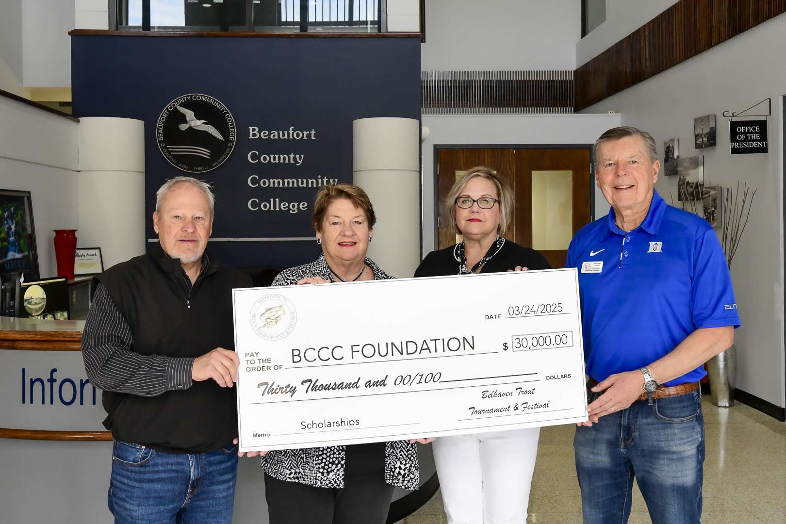 four people holding a big check