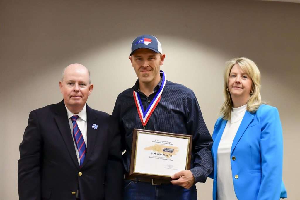 Three People, one with an award