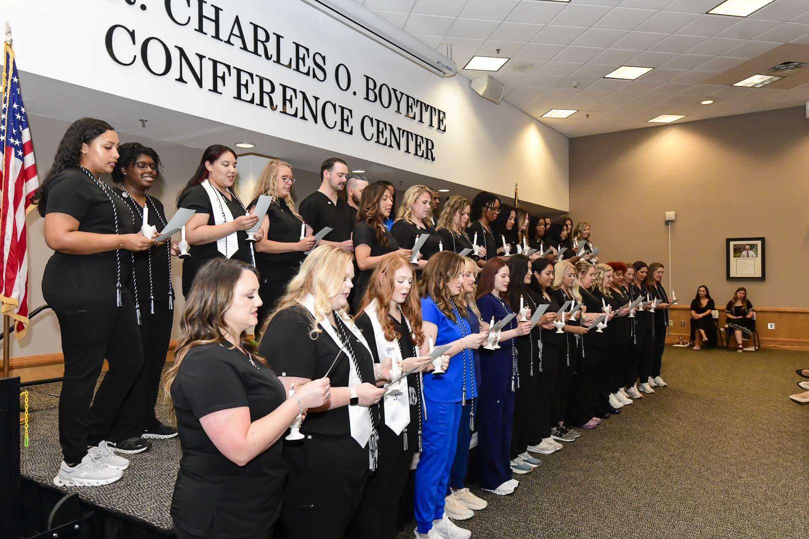 group in rows in black with text above "Charles Boyette Conference Center"