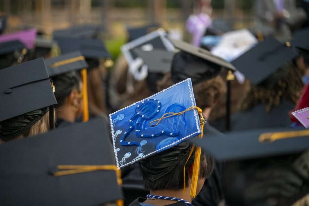 Students at graduation ceremony with camera focused on decorated graduation cap