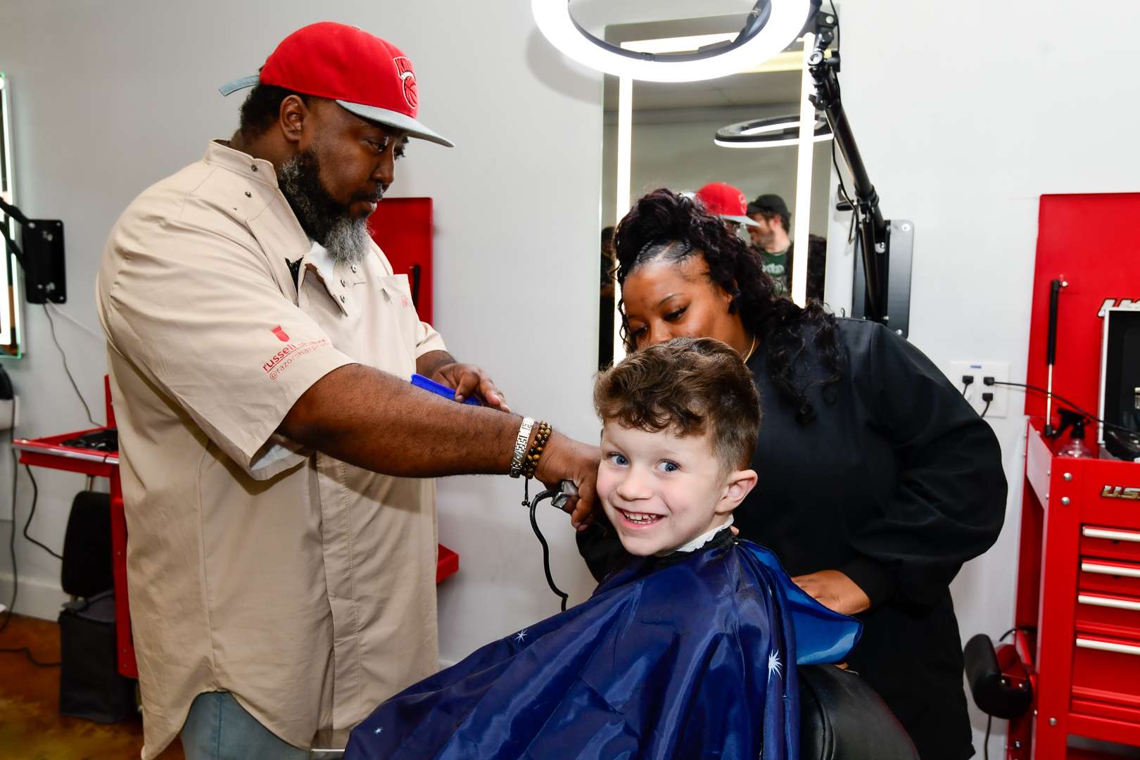 a child getting a haircut with an instructor and student