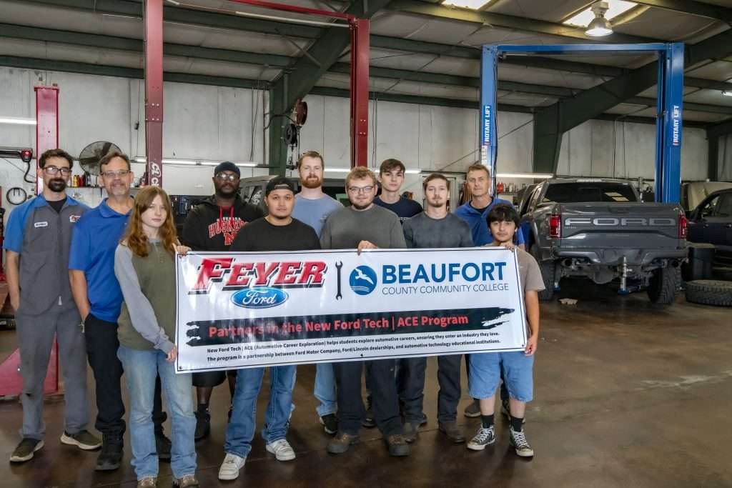 Group of people with a banner, text reading Feyer Beaufort, truck in background