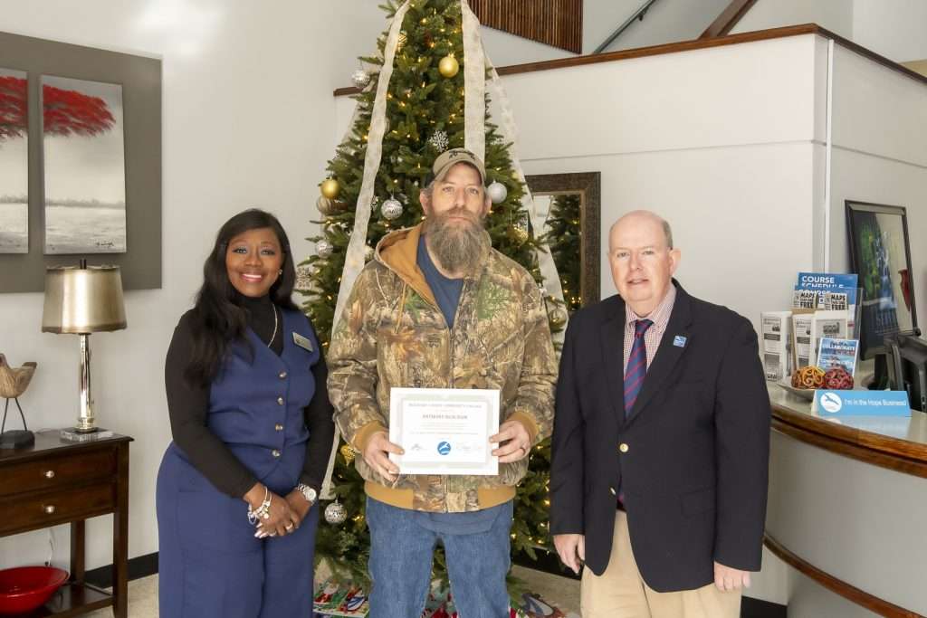 3 people, one holding an award