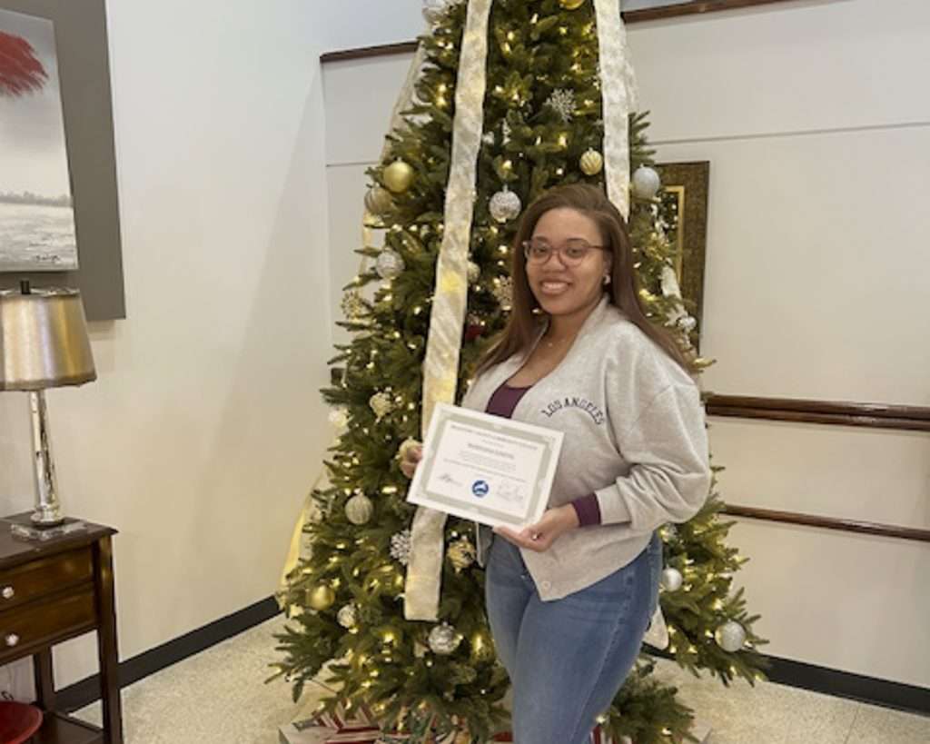 Person with an award in front of christmas tree