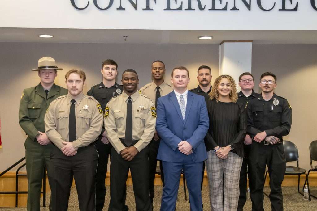 group of graduates in formal attire or law enforcement uniforms