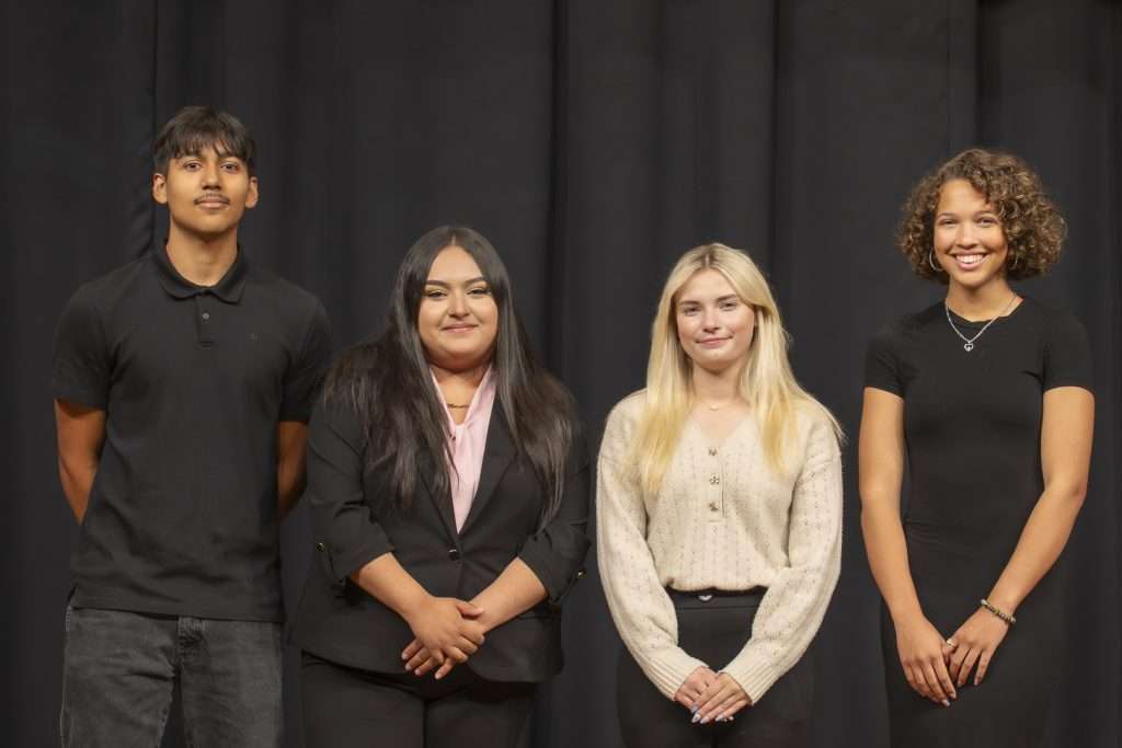 Four people in black on a black background
