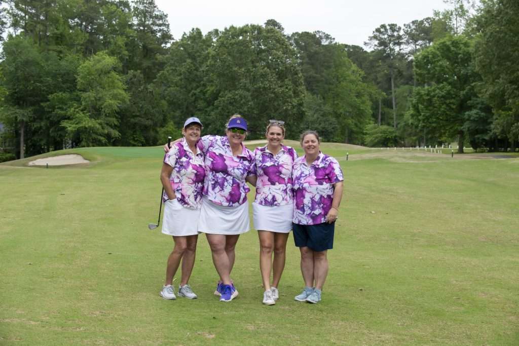 four people with brightly colored shirts on a golf course