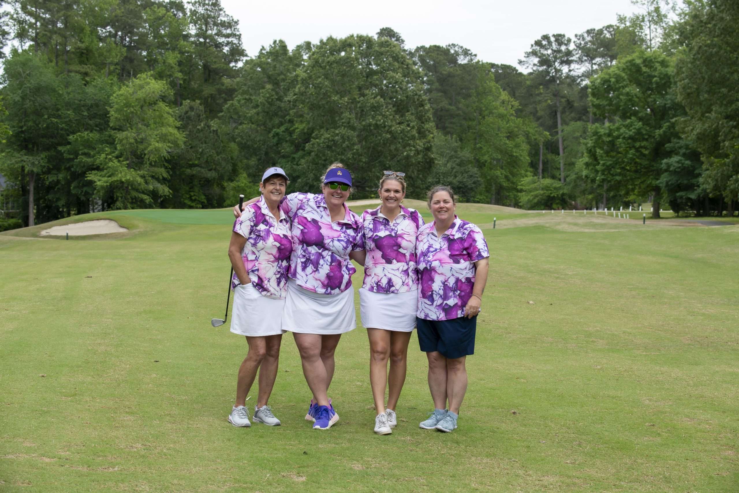 four people with brightly colored shirts on a golf course