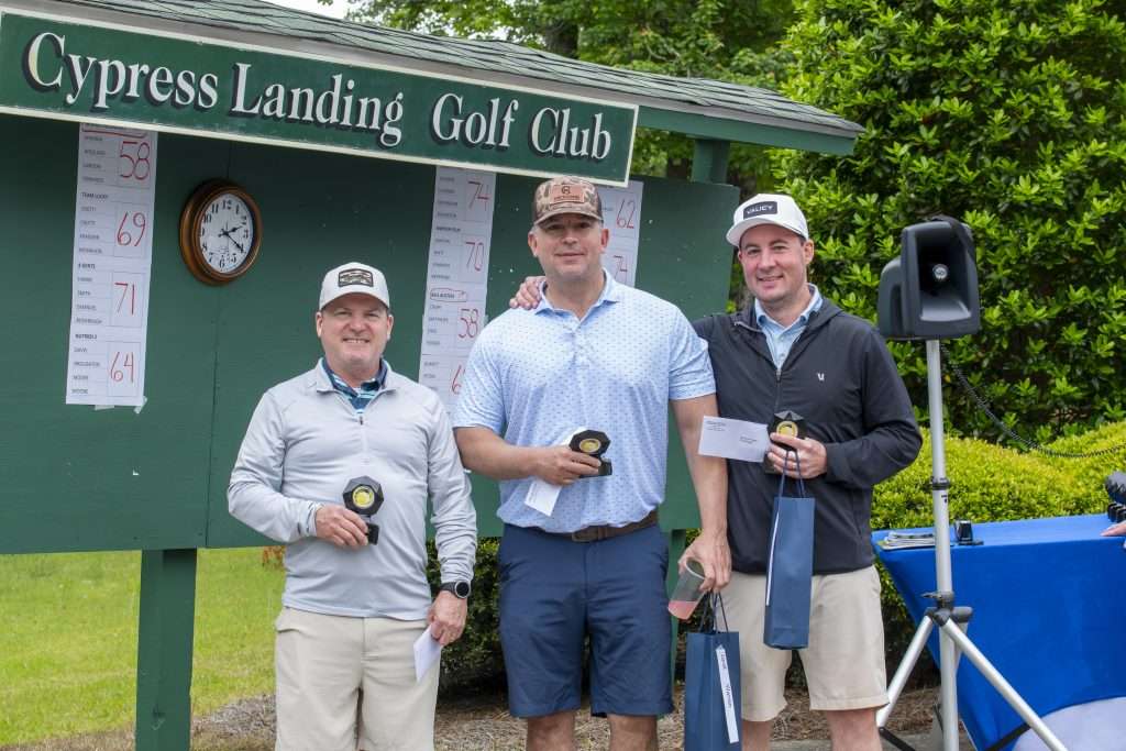 Three people in front of sign reading Cypress Landing Golf Club