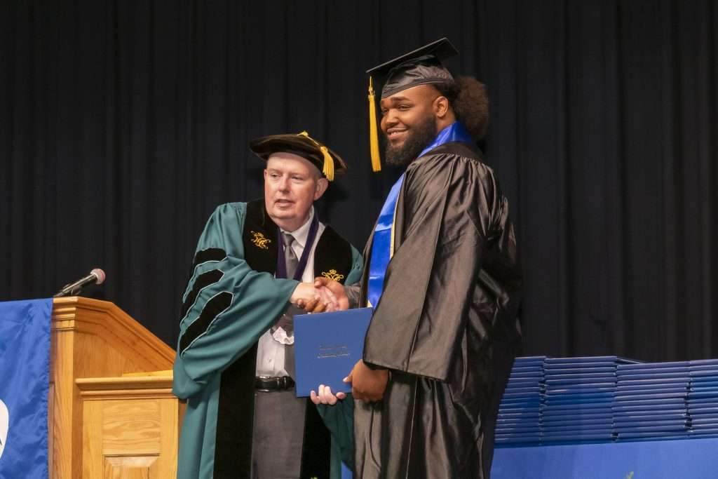 Two people exchanging a degree on stage at graduation