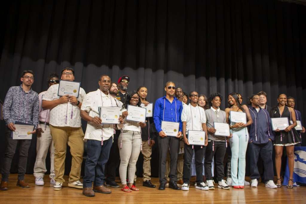 a group on stage with certificates