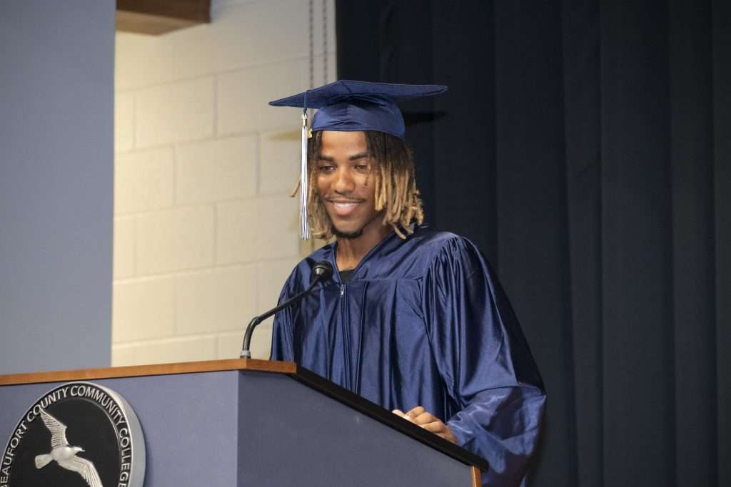 Man at opodium in cap & gown