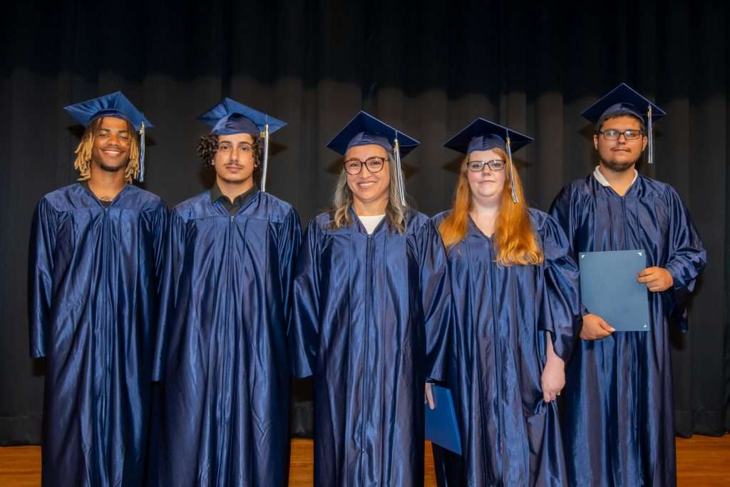5 people on stage in cap & gown