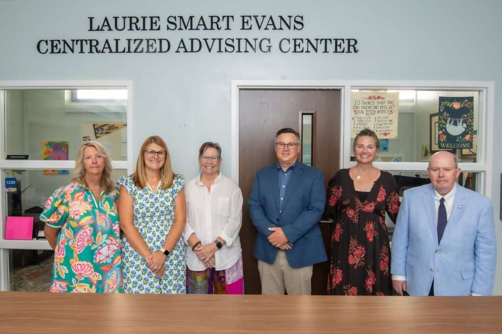 People under a sign reading "Laurie Evans Smart Centralized Advising Center"