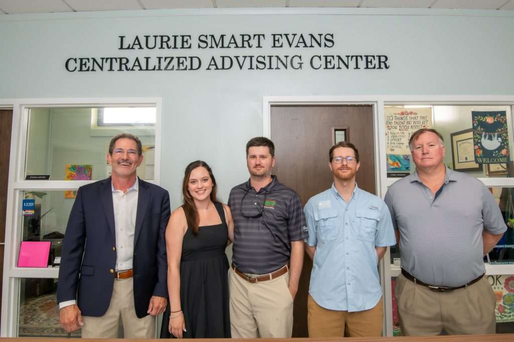 five people under a sign reading "Laurie Smart Evans Centralized Advising Center"