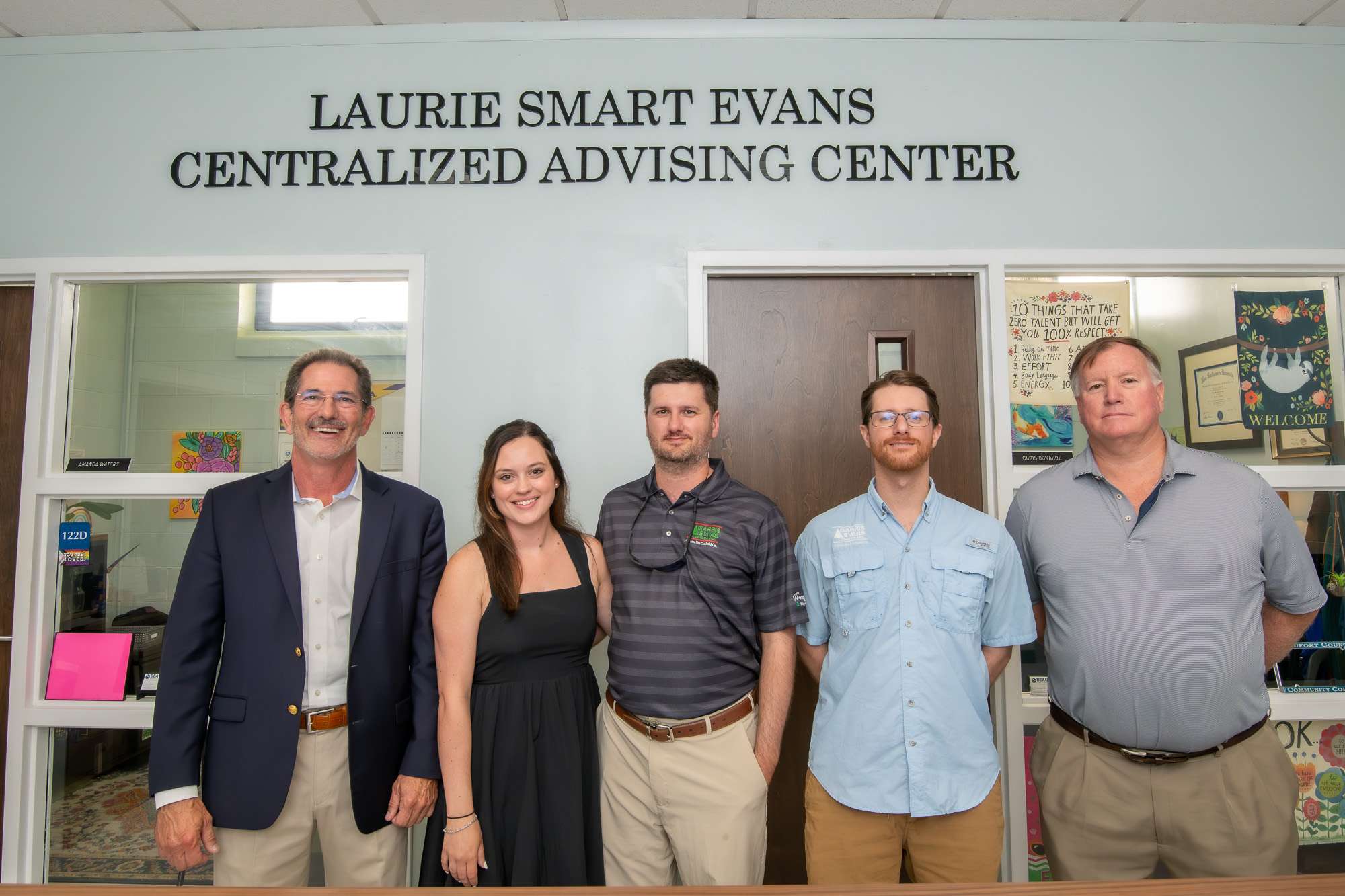 five people under a sign reading "Laurie Smart Evans Centralized Advising Center"