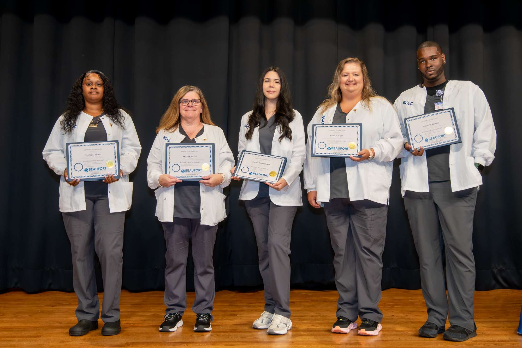 5 people in white coats with certificates